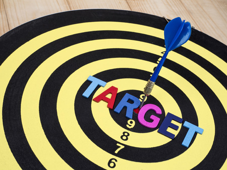 Word spell TARGET on dart board with blue arrow on isolated / white background with clipping path (Business Concept)の写真素材