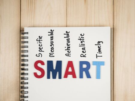 SMART Goals in notebook on wood background (Business Concept)の写真素材