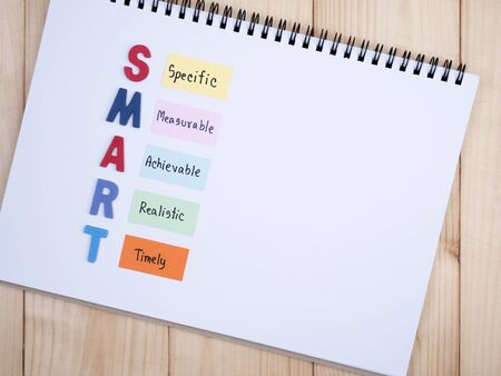 SMART Goals in notebook on wood background (Business Concept)の写真素材