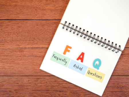 Word spell FAQ and handwriting frequently asked questions on notebook with dark wood background on top viewの写真素材