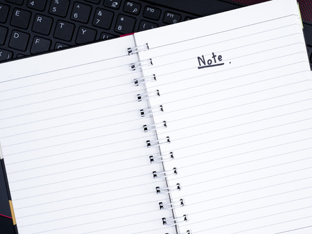 Handwriting note on white notebook with laptop keyboard (Top view)
