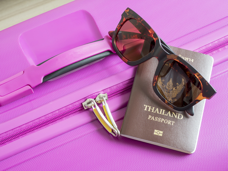 Closeup Thailand passport and sunglasses on pink suitcaseの写真素材