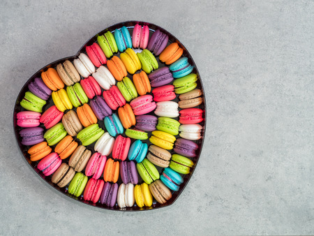 Top view of French colorful macarons in the heart shape box on bare cement backgroundの写真素材