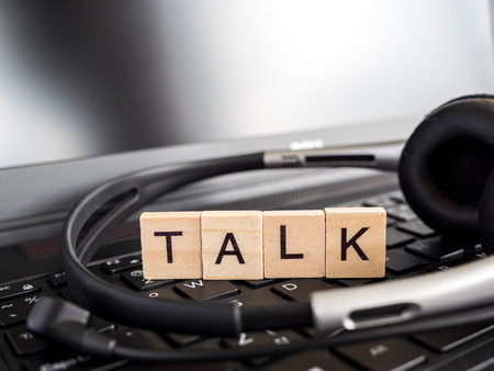 Word spell "Talk" over laptop keyboard and headset (Communication concept)の写真素材