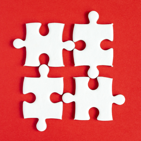 Closeup one white jigsaw puzzle beside missing jigsaw group on red background with top view (Business Concept)の写真素材