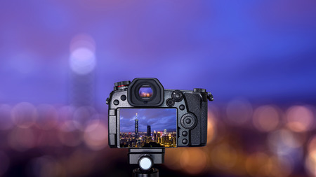 Digital camera over tripod on bokeh background of cityscape nightlife view of Taipei. Taiwan city skyline at twilight time, public scene from view point at Elephant Mountain Hiking Trail.の写真素材