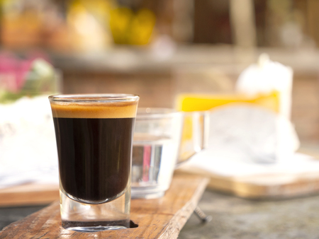 Closeup of a cup of coffee and cake on the table with sun light and copy space in warm tone.の写真素材
