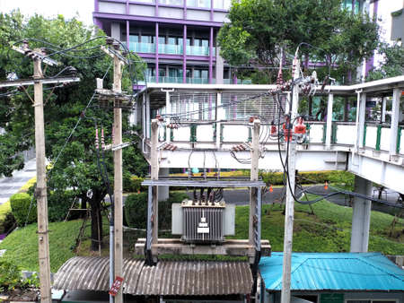 Electrical pole with transmission line, insulation, transformer. Next to condominium, Bangkok, Thailand.の写真素材
