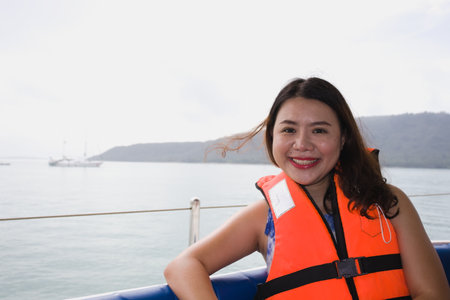 Portrait Asia woman wear life jacket on yacht for safety. Happy smiling.の写真素材
