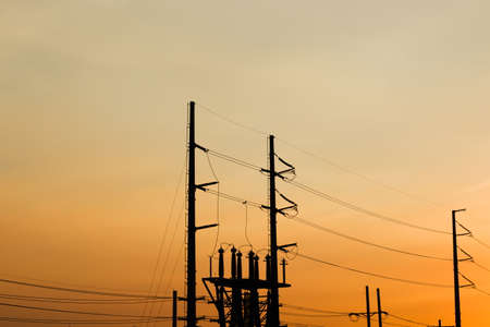 Silhouette High Voltage electric pole with background sunset orange sky.の写真素材