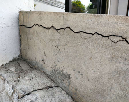 Crack cement concrete at pavement ground from vibration for long time. Reveal big gap from wall. Close-up.の写真素材