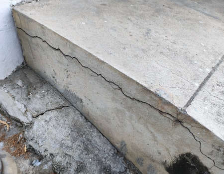 Crack cement concrete at pavement ground from vibration for long time. Reveal big gap from wall. Close-up.の写真素材