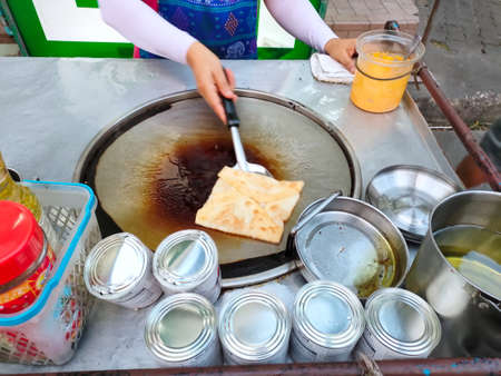 Bangkok, Thailand - March 1, 2021 : Woman cooking pancake roti, Thailand local street food. Adapt from India roti food. Desert or snack make from flour, sugar, condensed milk. Delicious and sweet.のeditorial素材