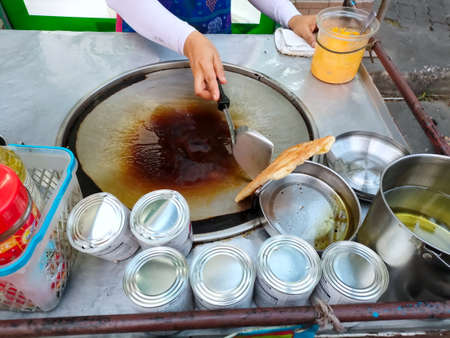 Bangkok, Thailand - March 1, 2021 : Woman cooking pancake roti, Thailand local street food. Adapt from India roti food. Desert or snack make from flour, sugar, condensed milk. Delicious and sweet.のeditorial素材