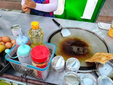 Bangkok, Thailand - March 1, 2021 : Woman cooking pancake roti, Thailand local street food. Adapt from India roti food. Desert or snack make from flour, sugar, condensed milk. Delicious and sweet.のeditorial素材