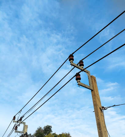 Electric pole with power line on blue cloudy sky background.