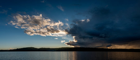 Panoramic view of storm clouds over the lake at sunset.の写真素材