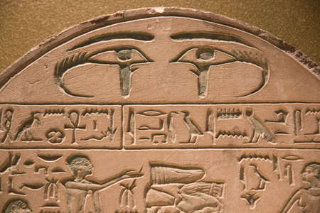 Leiden, The Netherlands - JAN 26, 2019: exhibition Gods of Egypt. Ancient Egypt hieroglyphics on a stela with two eye symbols on the top. Editorial image.のeditorial素材