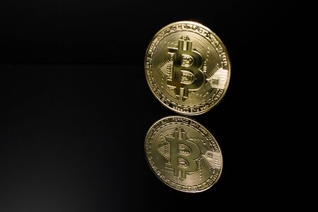 Closeup of a golden bitcoin coin with reflection and a dark black background. crypto currency. BTC.の写真素材