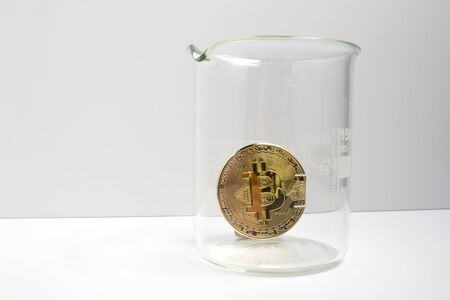Closeup of a BTC bitcoin coin in a laboratory beaker, ready for an experiment. The science of crypto...
