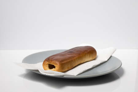 A home made Dutch sausage roll on a plate with a white background focused on the front of the sausage roll. Sausage roll.の写真素材
