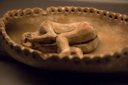 Leiden, The Netherlands - AUG 07, 2021: closeup of an old handcrafted plate with a human figurine laying in the fetus position from ancient Malta.のeditorial素材