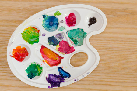 close-up of a palette with smudges of paint on a wooden surfaceの写真素材
