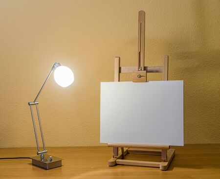wooden painting easel and a lit modern lamp
