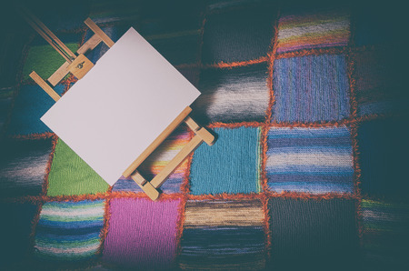 painting easel with blank canvas on a colorful patchwork