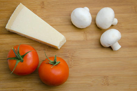 Parmesan cheese with tomatoes and mushrooms on wooden tableの写真素材