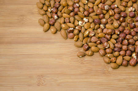 mix of almonds and hazelnuts in the corner of a wooden tableの写真素材