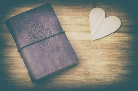 old notebook and a cardboard heart on a wooden table in vintage lookの写真素材