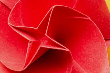 Abstract macro of a red stylized paper origami rose flower with plus shape in the middle. Top view.の写真素材