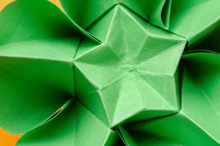 Abstract closeup of a green paper origami flower with star shape in the middle. Top view.の写真素材