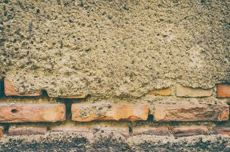 old decaying cement wall with a layer of bricks underneath showing through the weathered exterior. vintage filter effects.の写真素材