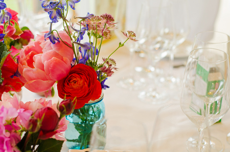 closeup of flowers and empty set wine glasses on a table at a wedding partyの写真素材
