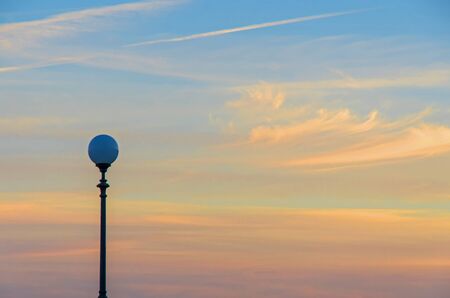 vintage lamp post in front of  beautiful sky  with sunlit orange clouds at sunset