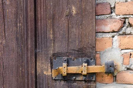 old decaying metal lock on a wooden door in a brick wall