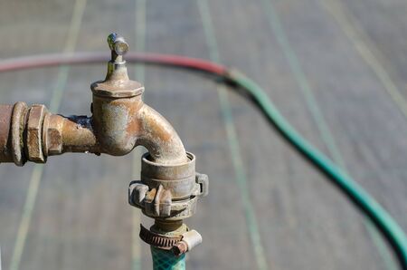 old rusty metal tap with a flexible hose attached to itの写真素材
