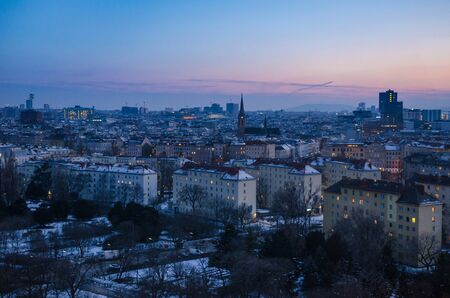 A winter evening sets over Vienna as the sun disappears and the many windows of the city begin to light upの写真素材