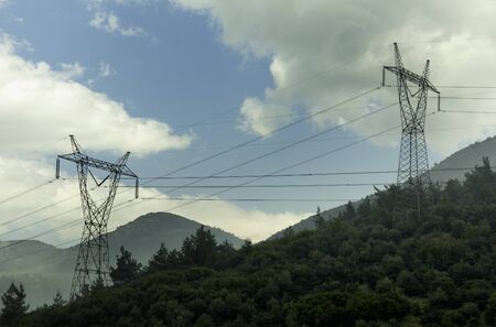 Electricity pylons cutting through forest. Electric power lines at Mountainの写真素材