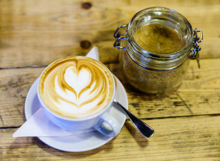 Cappuccino Coffee on the wooden table with brown sugarの写真素材