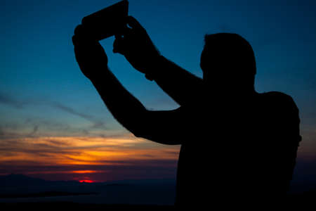 Taking selfies with mobile on sunsetの写真素材