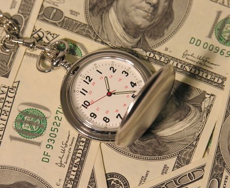A photo of a pocket watch on hundred dollar bills