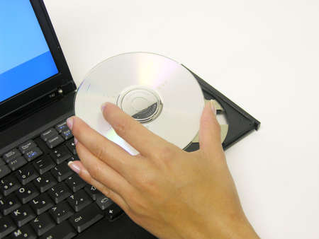 A photo of a woman placing a DVD into a laptop