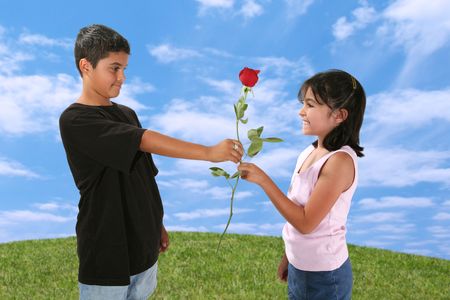 Young boy giving a young girl a red roseの写真素材