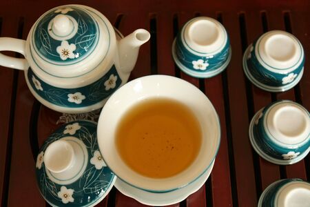 A tea pot and several cups being served