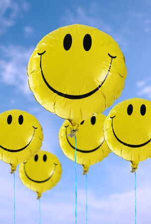 A smiley faced balloon in the blue skyの写真素材