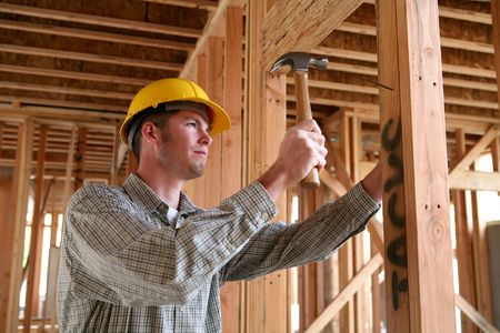 A handsome construction man using a hammer to nail together wood
