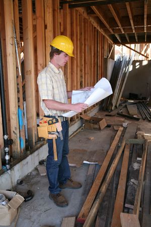 A male construction worker reading the blueprints at a home construction site